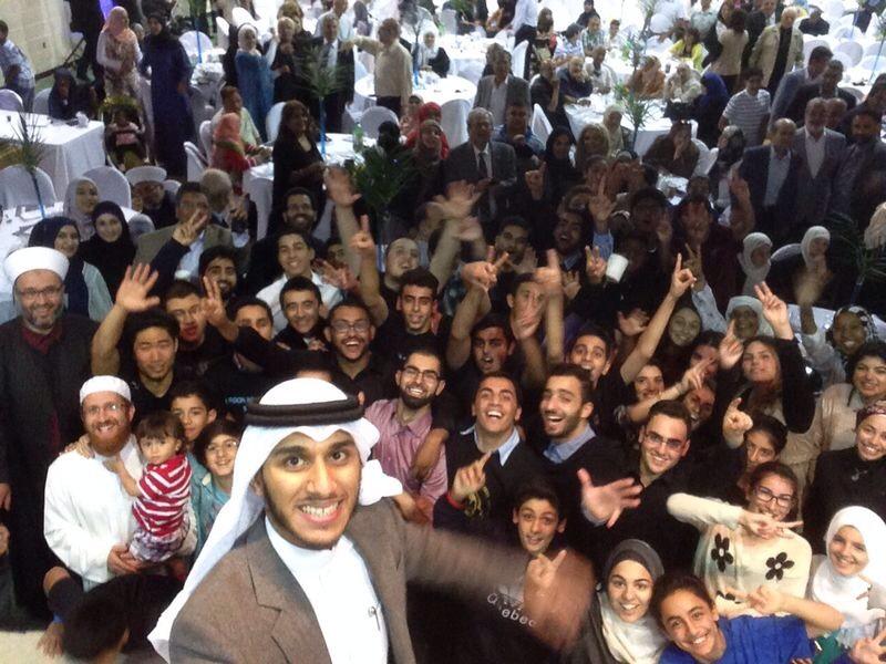 A man takes a selfie with 50+ people behind him celebrating